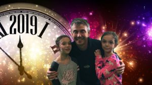 man hugging two girls with large clock in the background