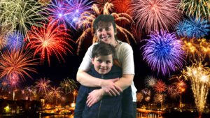 woman hugging a boy with fireworks in the background